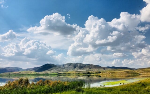 Picture of a lake and mountains in the background with some clouds overhead.